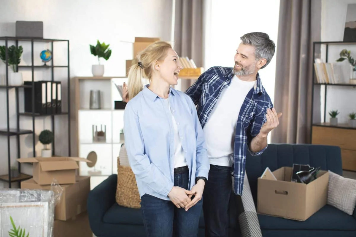 Couple souriant devant un appartement à Meribel pour investissement locatif